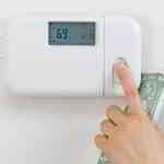 person lowering thermostat setting