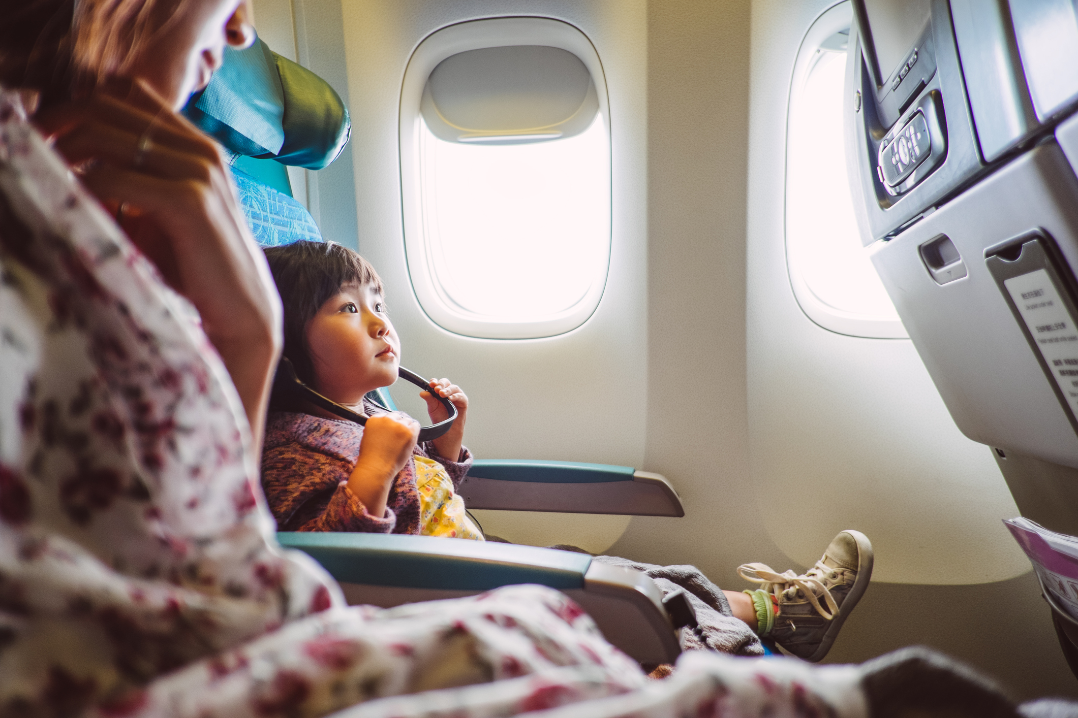 A child and mother sit in an airplane getting ready to leave for vacation