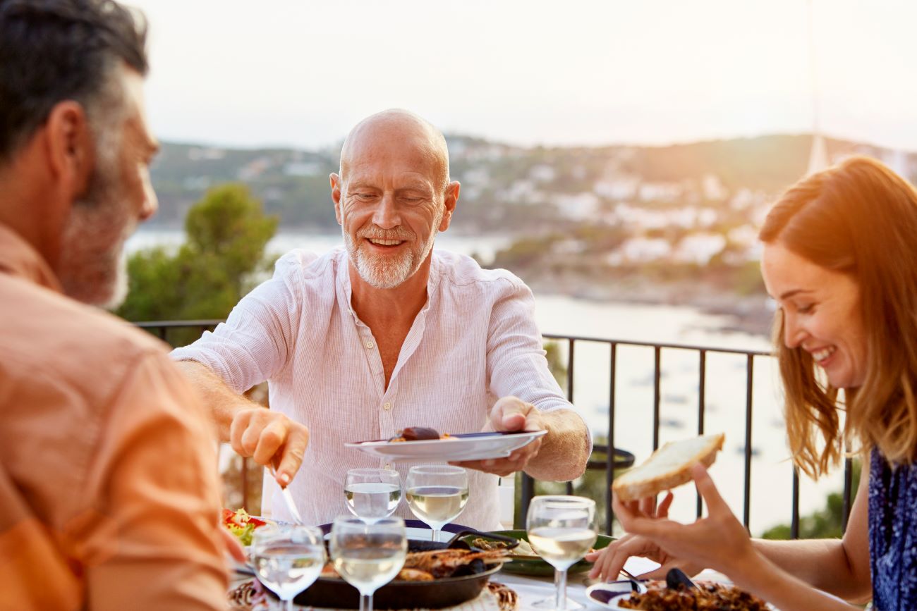 a group of friends dines outside with the ocean as a backdrom