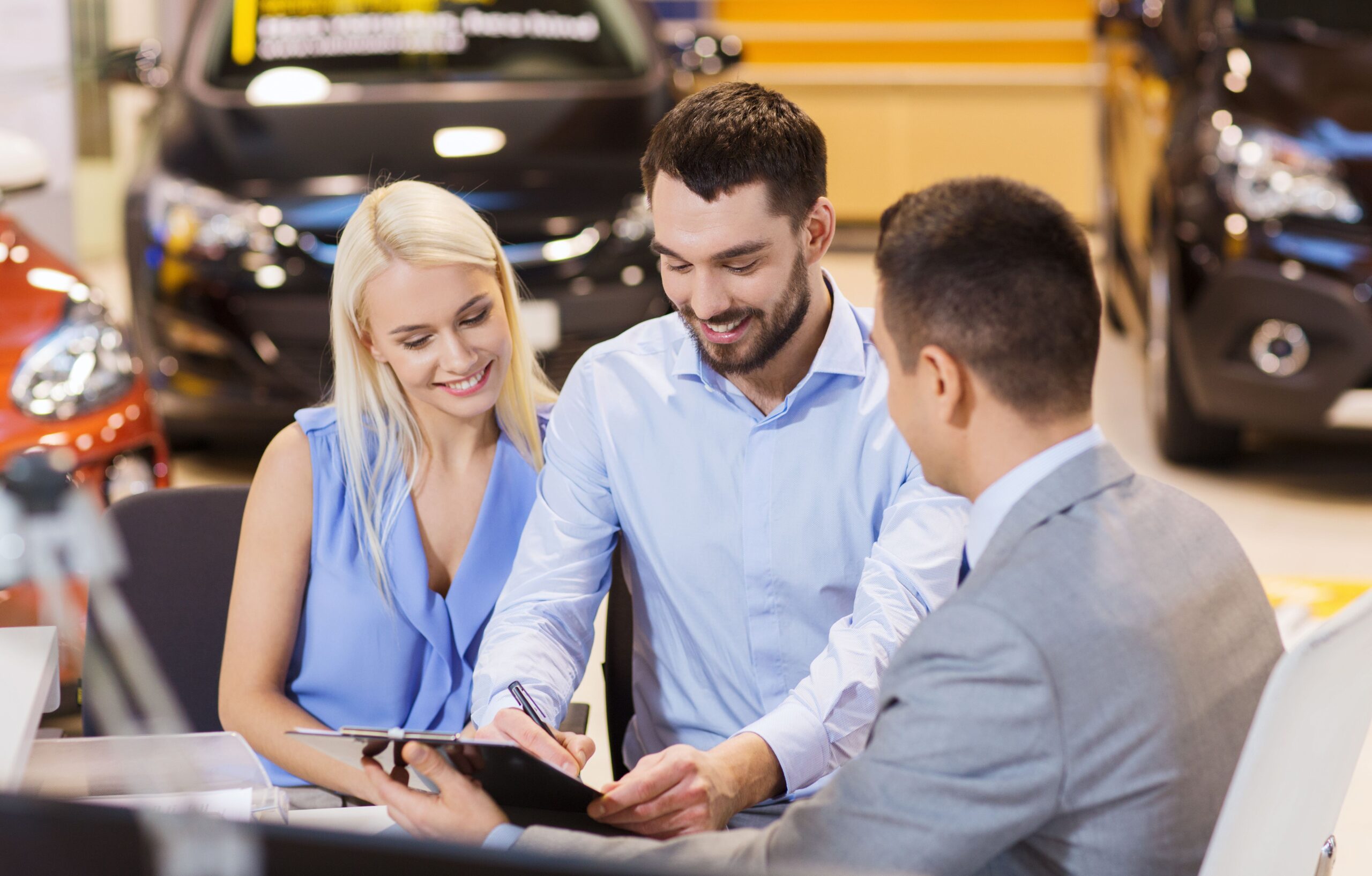 couple signing their car document with salesmen
