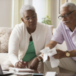 Retired couple paying bills with laptop