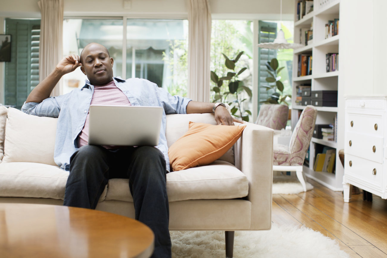 Man using laptop at home wonders if he's fallen victim to a personal loan scam.