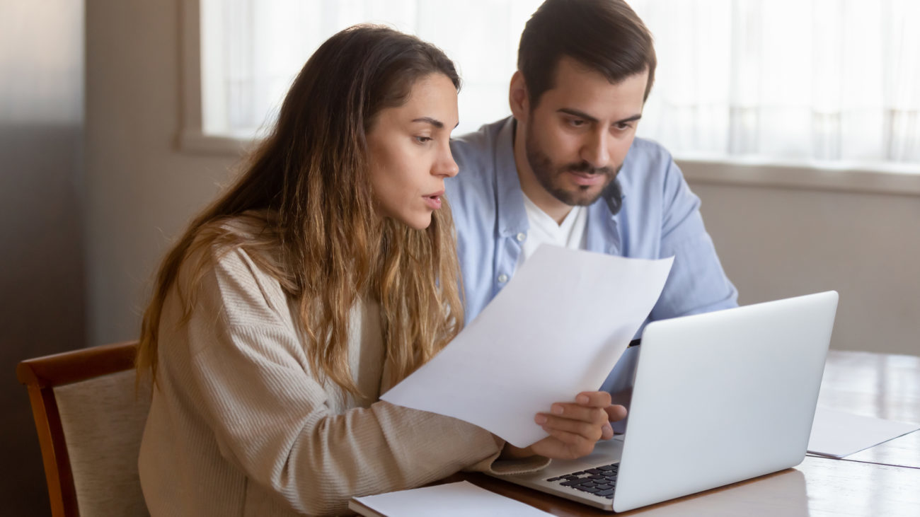 A married couple discusses their personal loan options while looking a their bills and their computer.