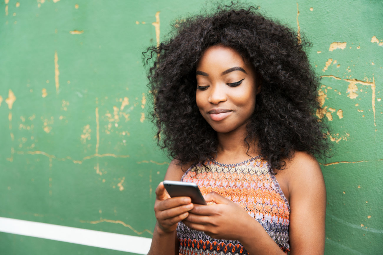 A young woman uses her phone to research personal loan lenders.