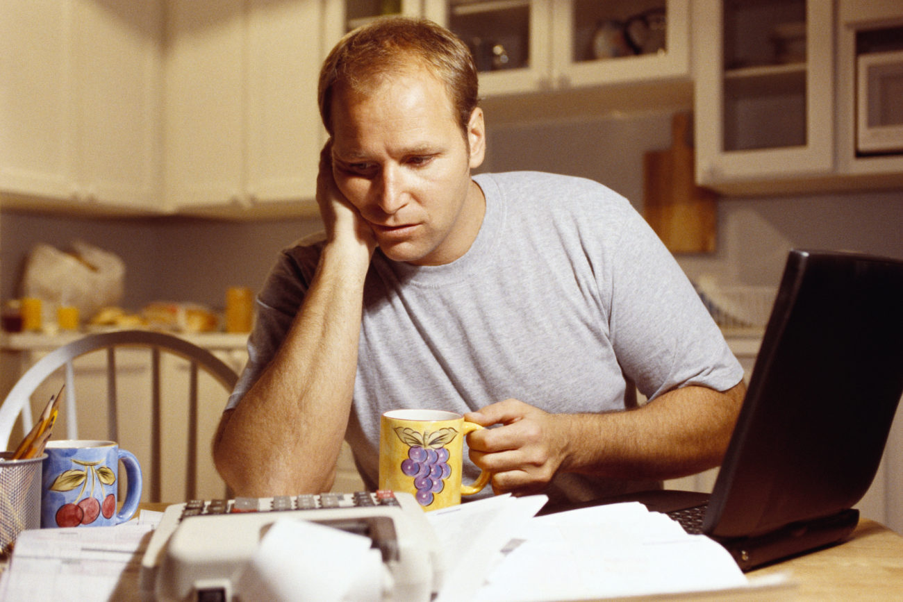 A man sits at his kitchen table with his laptop