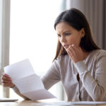 A woman with a concerned expression looks at her credit report