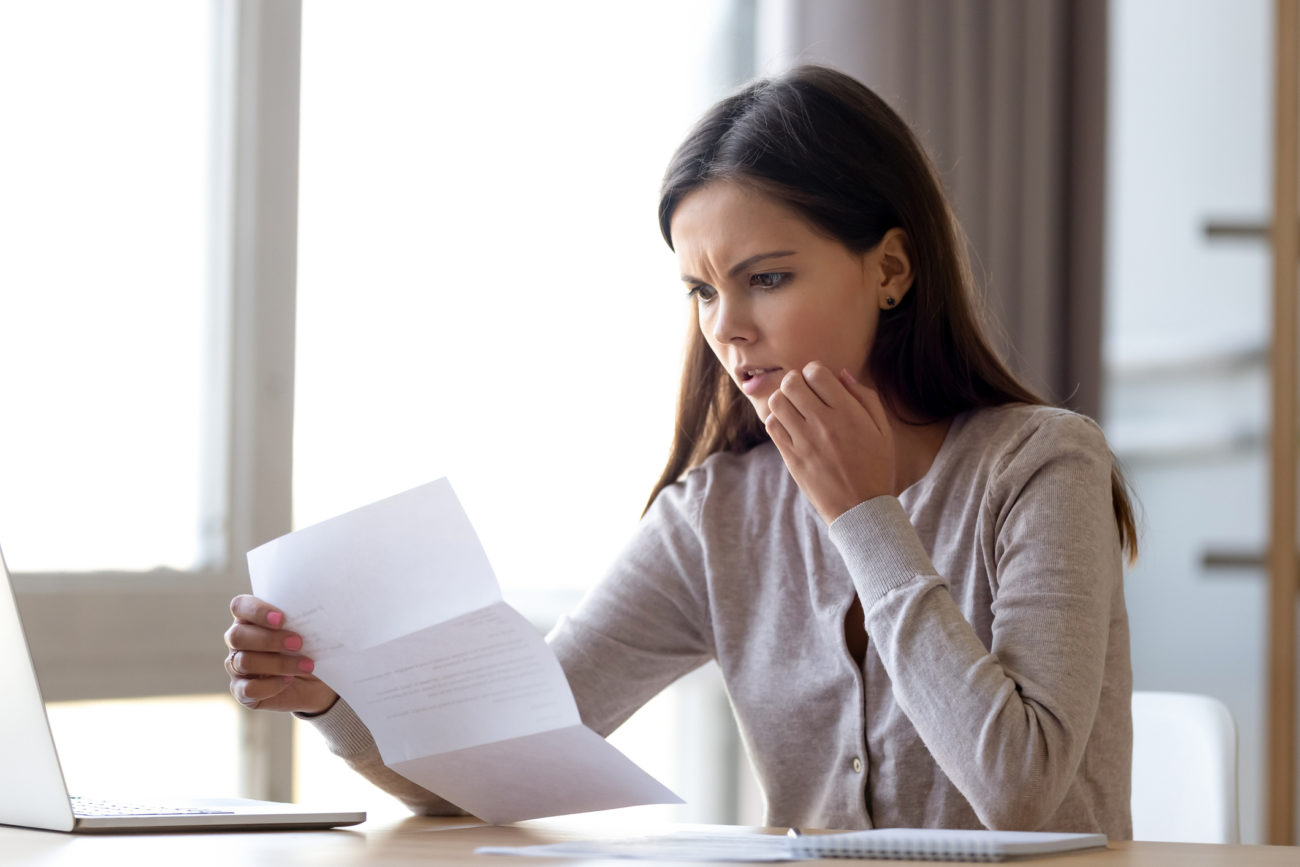 A woman with a concerned expression looks at her credit report