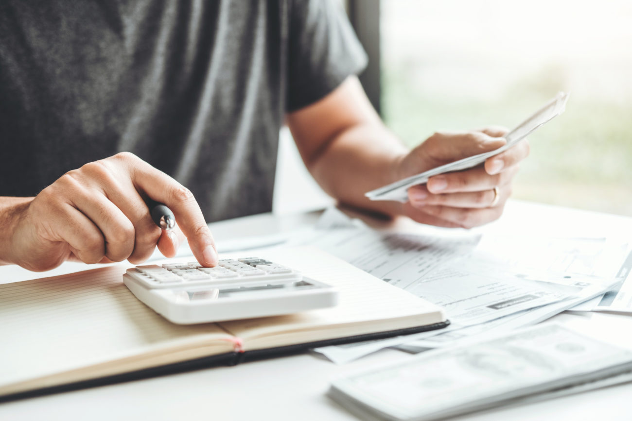 A man uses a calculator to work on his post-COVID finances