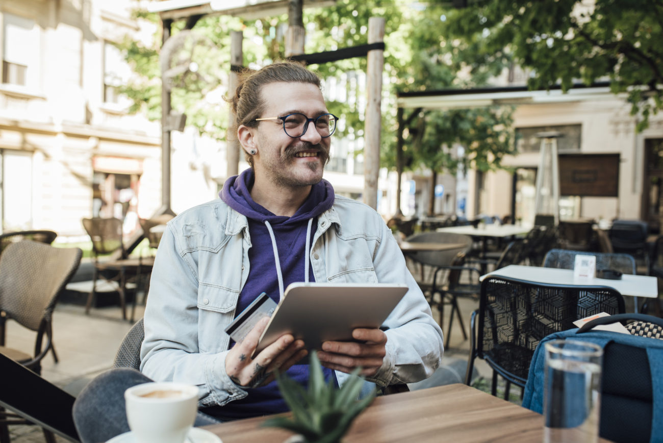 A young man sits outside as he uses his tablet to apply for a personal loan.