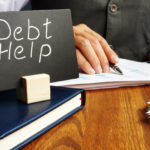 a man works on debt consolidation with a debt help sign on his desk