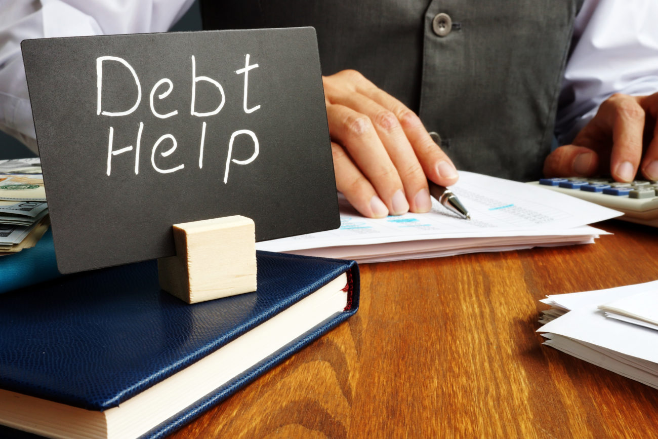 a man works on debt consolidation with a debt help sign on his desk