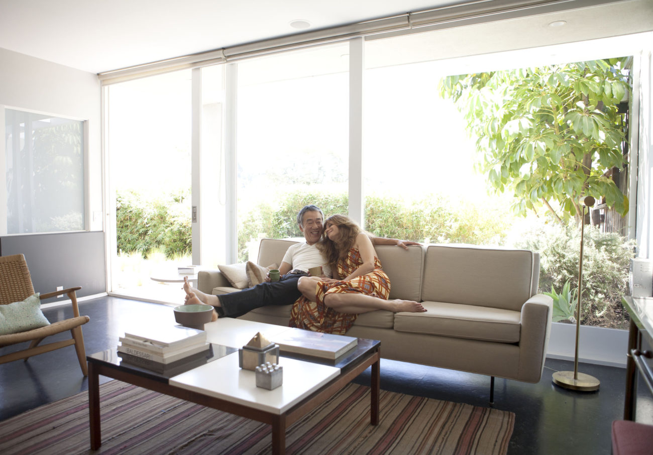 A married couple sit on a couch in a contemporary living room