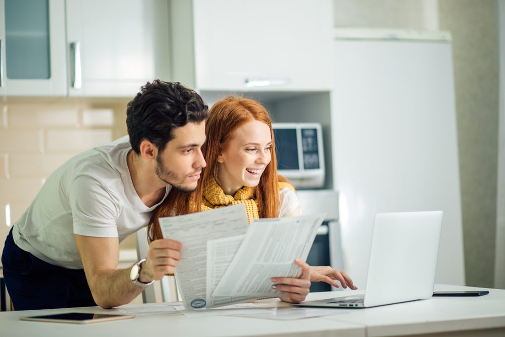 A couple pays bills at home using their computer