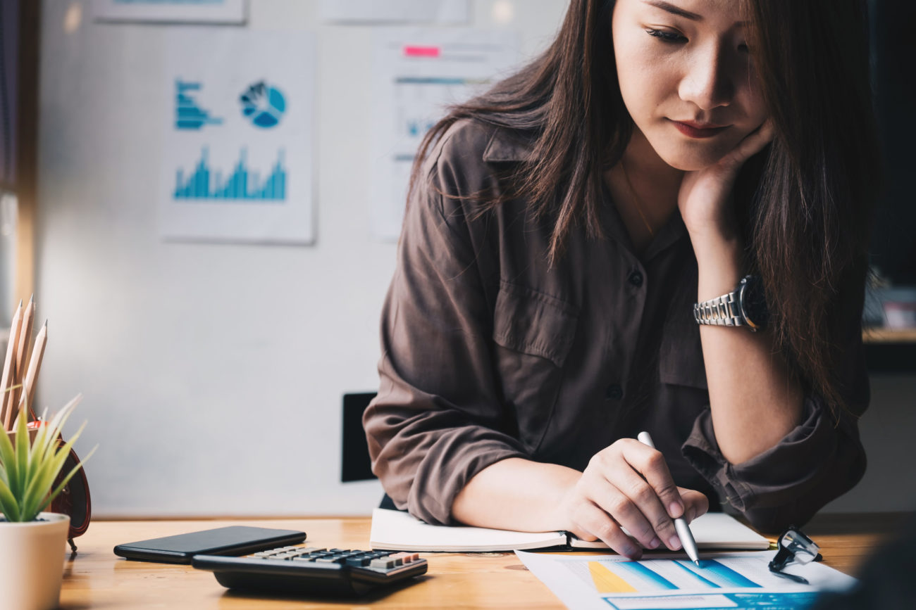 A woman uses a calculator to find out how long it will take her to pay off a personal loan