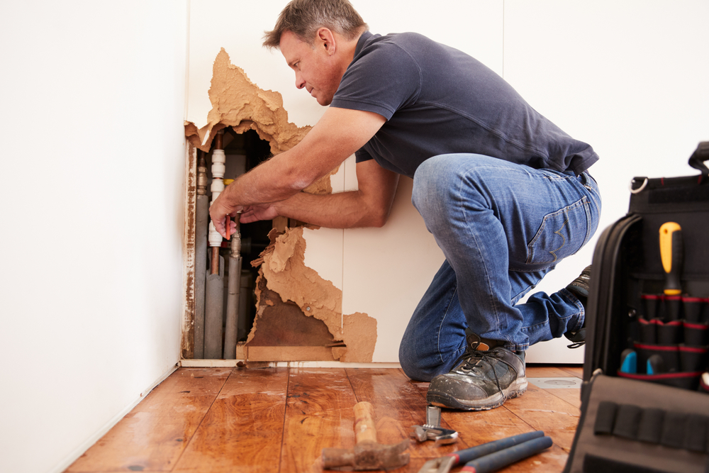 A man repairs damage to his home after a flood