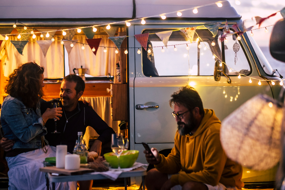 Three people enjoy dinner outside together while their travel fan can be seen decorated behind them.