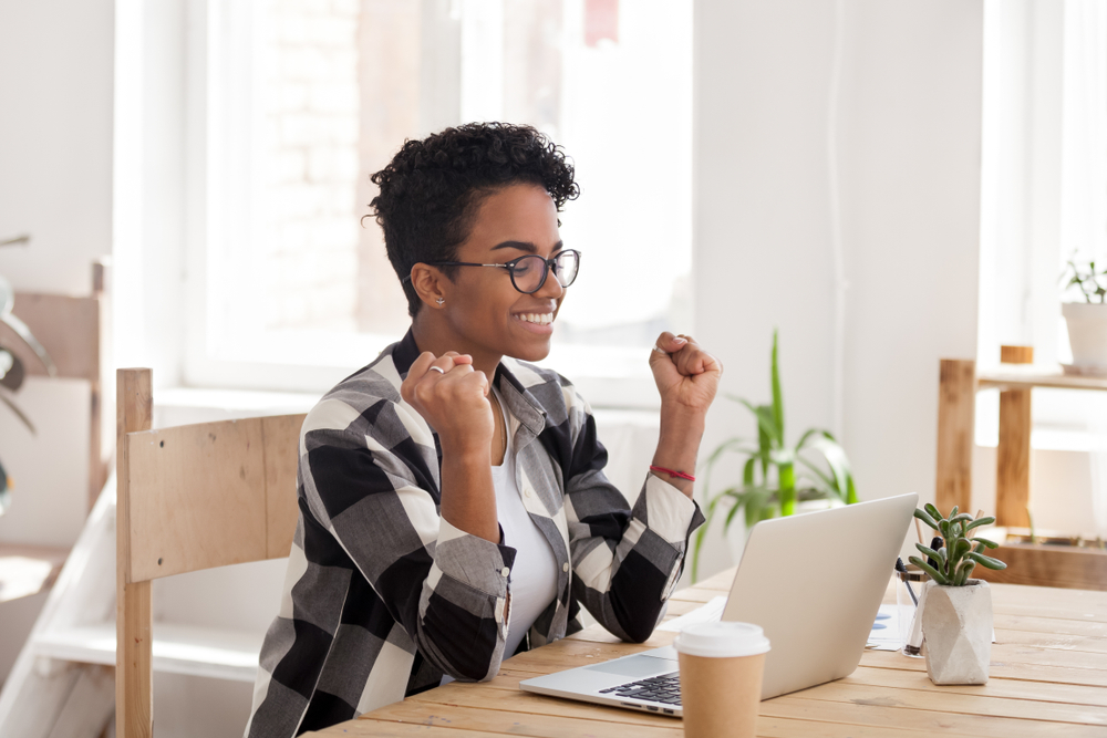 A woman is sitting in front of her computer looking happy because she just got approved for an online personal loan