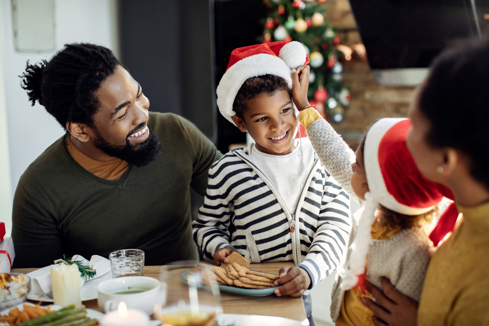 A happy family celebrates Christmas with a tree and Santa hats