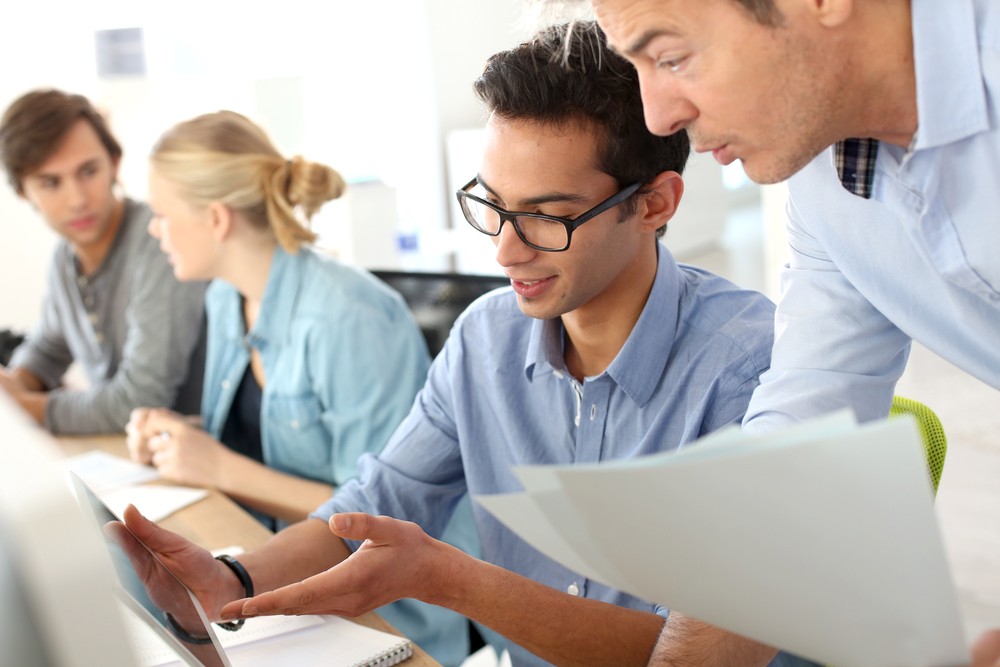 A group of interns receive instruction from a company employee at work