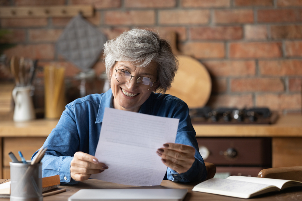 A woman looks at a loan prequalification letter with a smile on her face