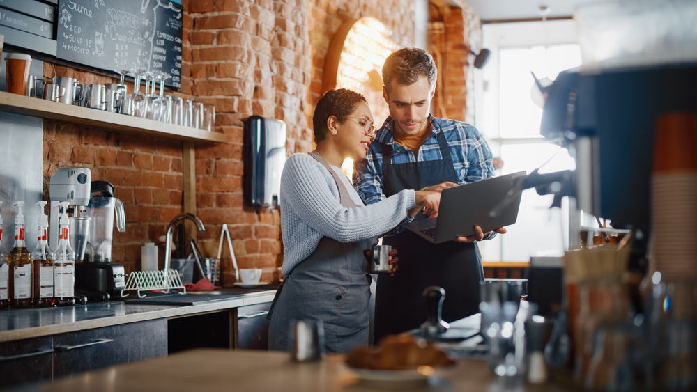 Small business owners look at a computer and discuss their personal loan options