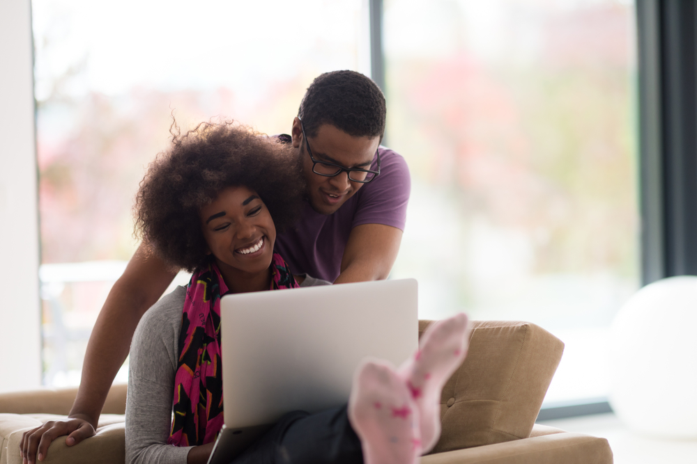 A happy couple look at their computer and see that they have been approved for a personal loan