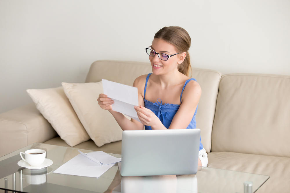 A happy woman is looking at a letter she received in the mail letting her know that her personal loan has been paid off